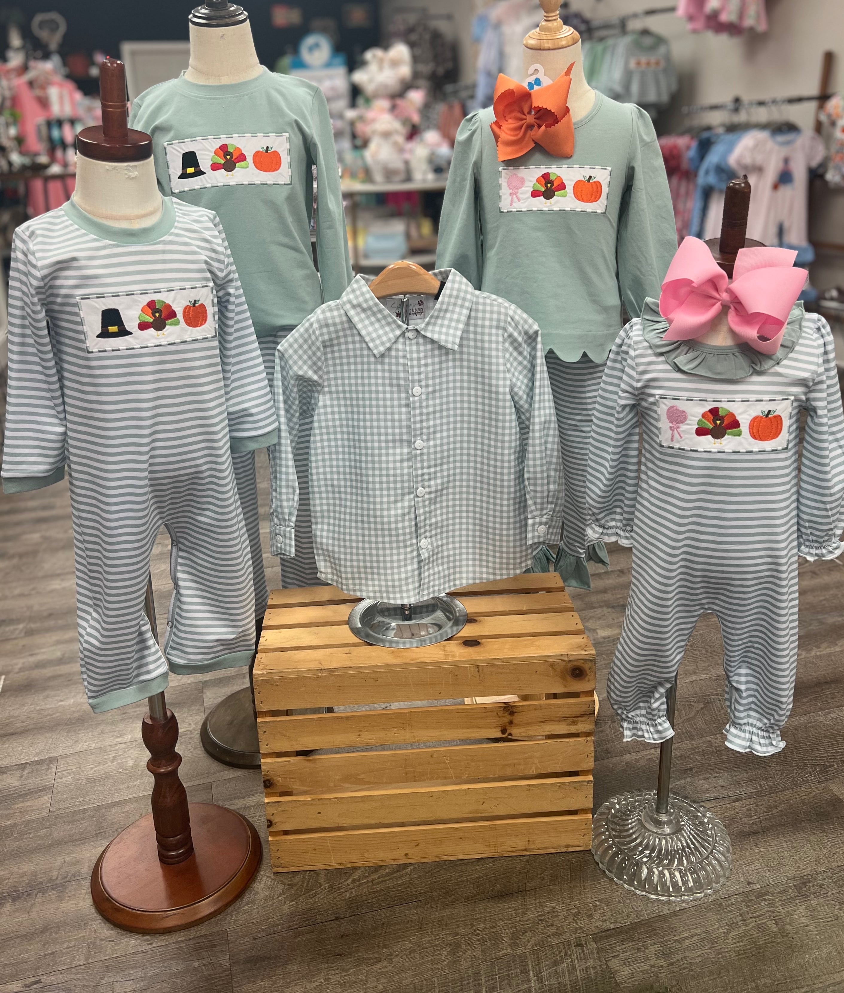 Children's clothing with festive designs on mannequins in a store setting.