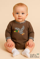 Baby wearing a brown bubble with a duck design.