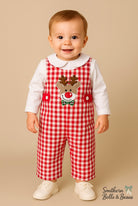 Baby wearing a red checkered outfit with a reindeer design on a beige background