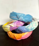 Colorful tie-dye hairbands stacked on a dark surface with a white background