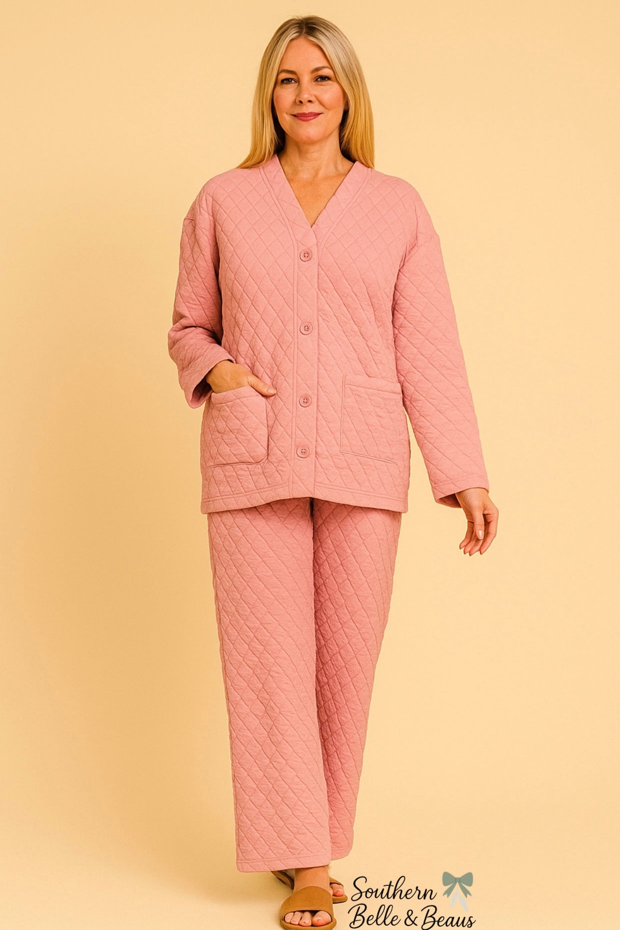 Woman wearing a pink quilted pajama set against a beige background