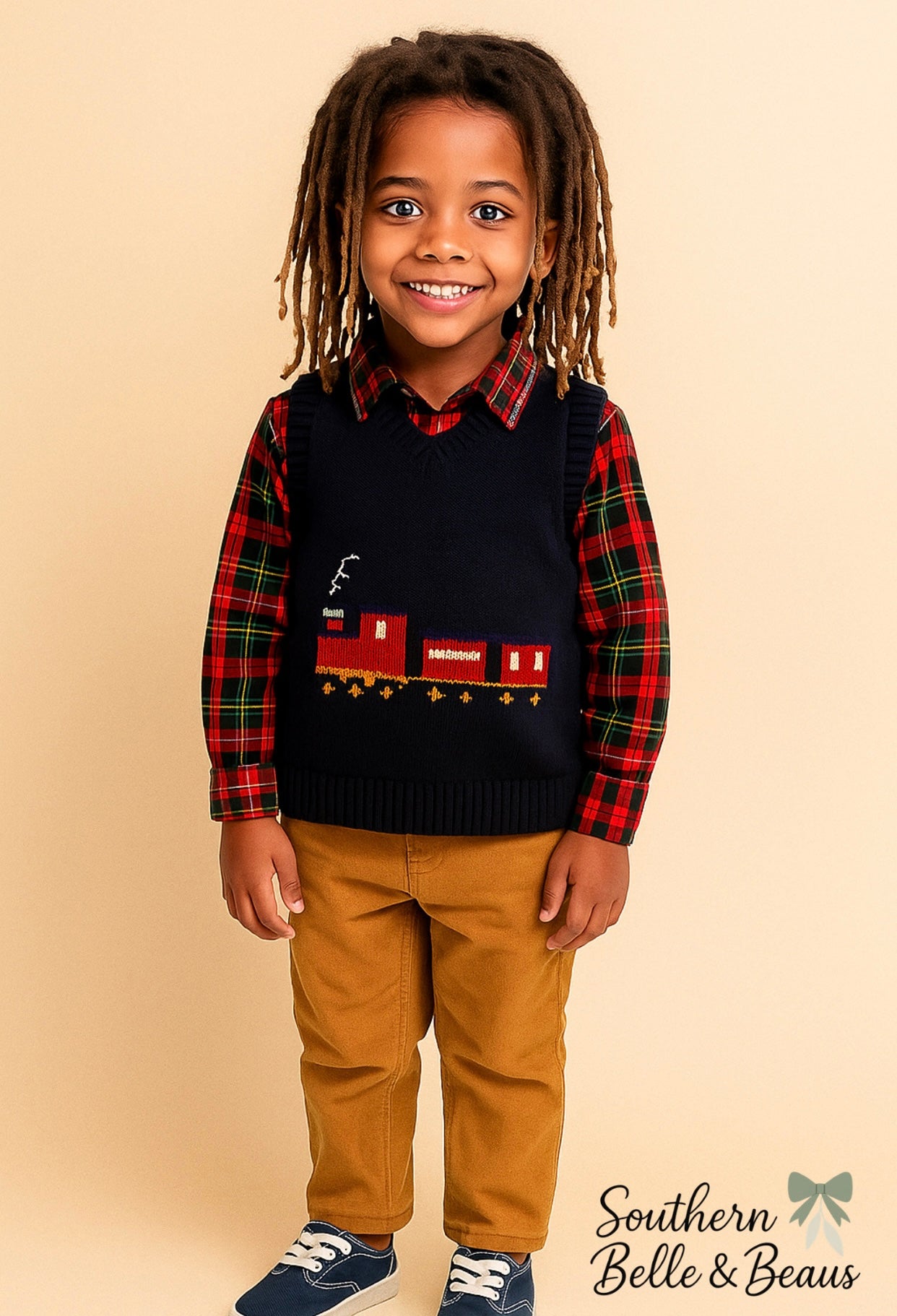 a cozy navy sweater vest with a cheerful train applique, paired with a classic red-and-green plaid button-down shirt and soft tan corduroy pants.