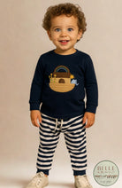Little boy wearing navy Noah’s Ark embroidered top with striped jogger pants.