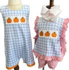 Two children's outfits with blue and pink checkered patterns and pumpkin patches on a white background.