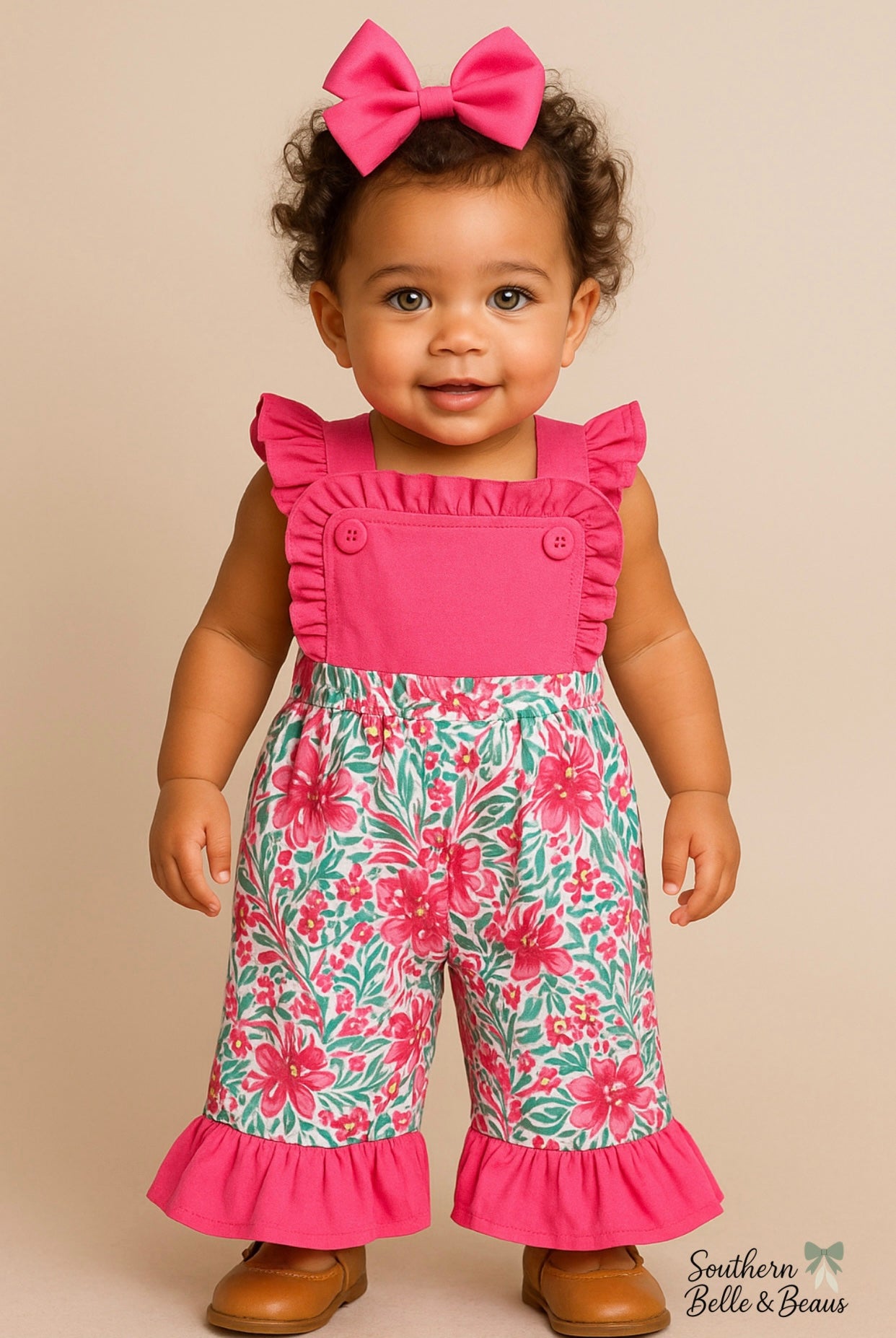 Child wearing a pink top and floral overalls with a bow on a beige background