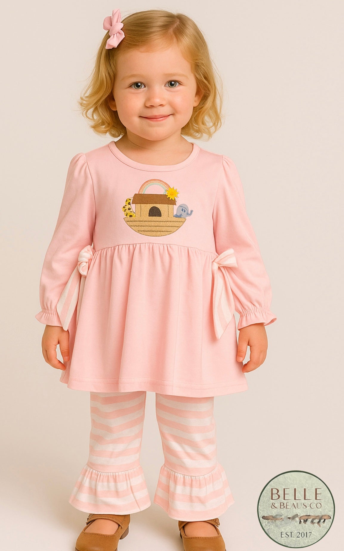 The tunic-style top ties with soft side bows and pairs perfectly with coordinating pink-and-white ruffle pants.