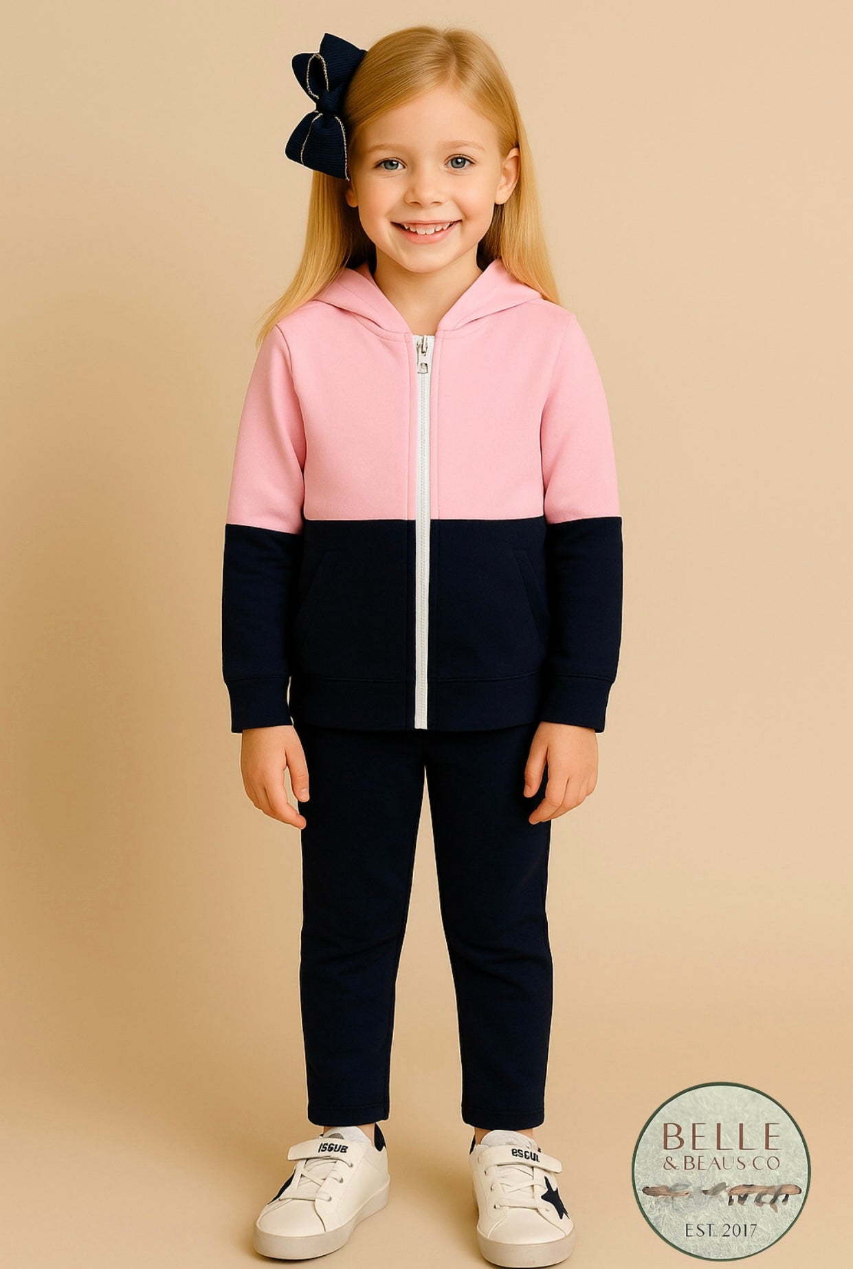 Pink and navy colorblock girls hoodie named “Zuri’s Zip-Up” displayed with matching navy bow and white sneakers from Southern Belle & Beaus.