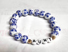 A bracelet with white and blue ceramic beads, and gold accents, spelling out 'GIGI'