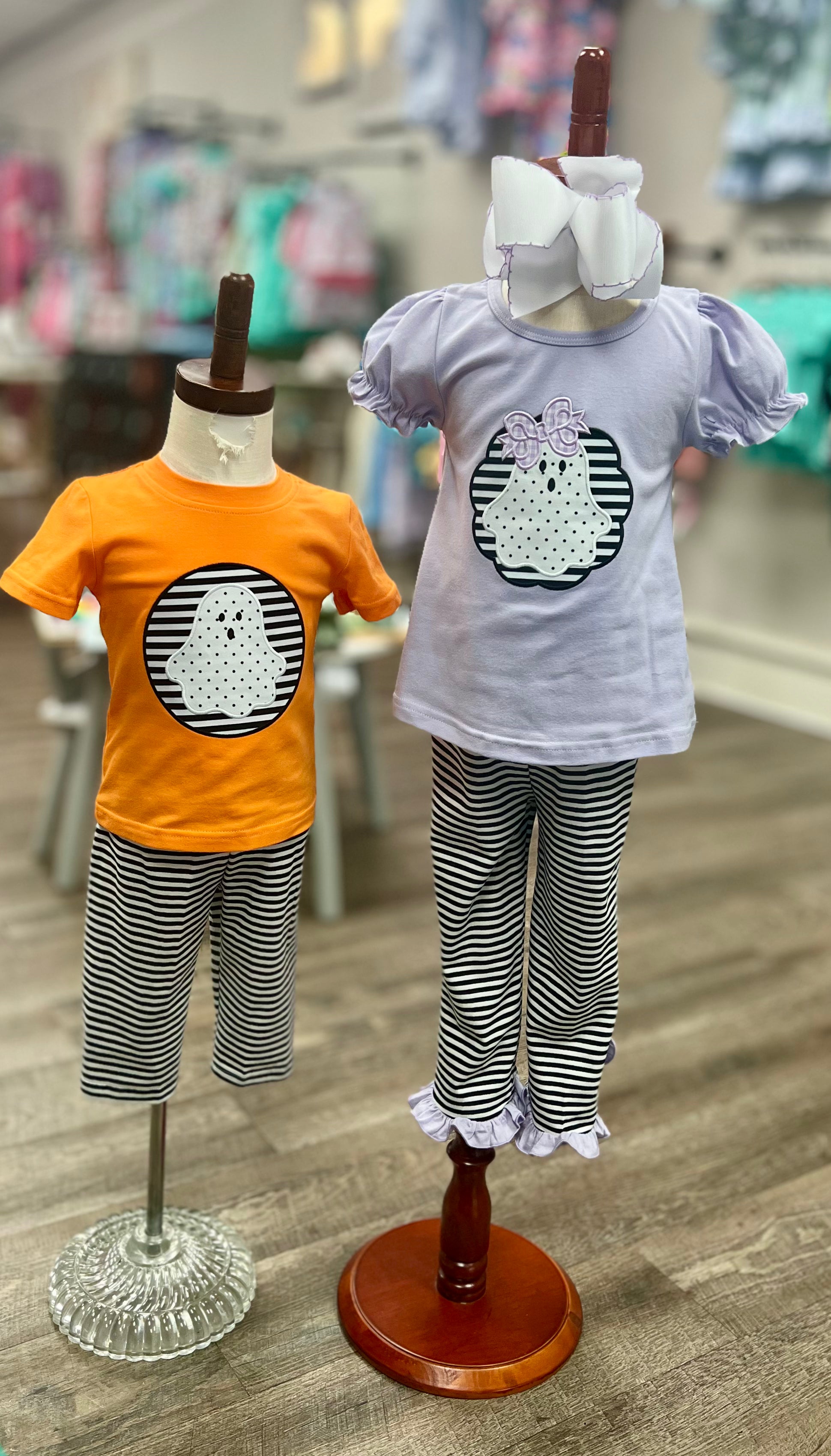 Two children's outfits on mannequins with a blurred store background