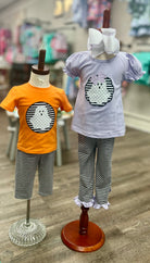 Two children's outfits on mannequins with a blurred store background