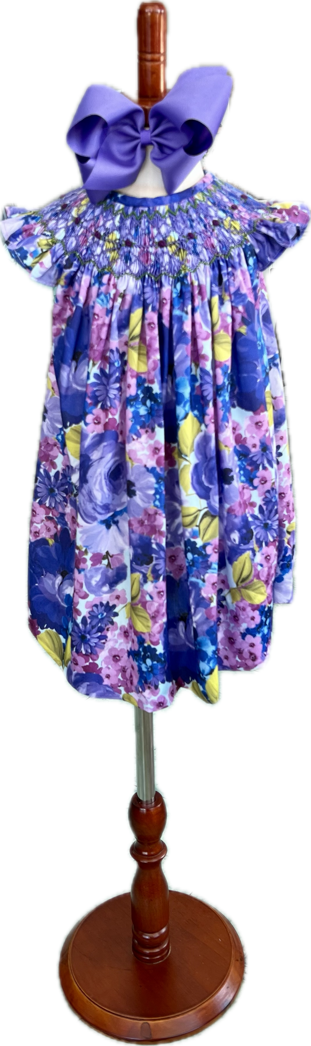 Children's floral dress on a mannequin with a large purple bow.