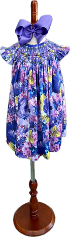 Children's floral dress on a mannequin with a large purple bow.