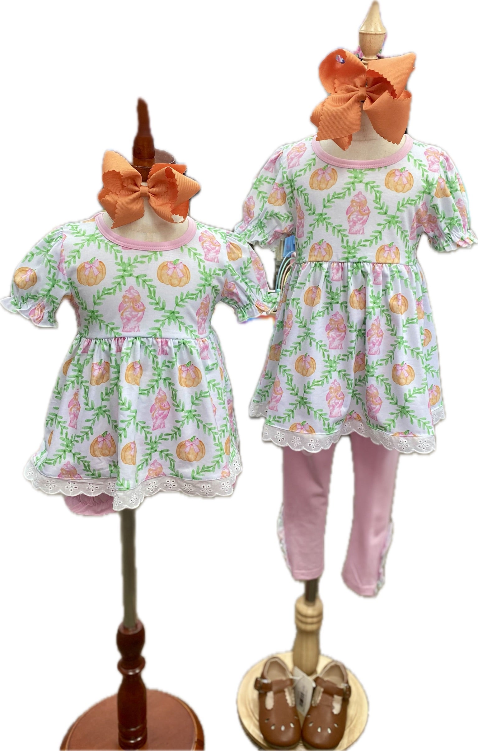 Two children's outfits on mannequins with floral patterns and orange bows.