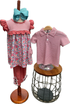 Children's outfit with floral dress, striped shirt, and blue headband on mannequin and stool.