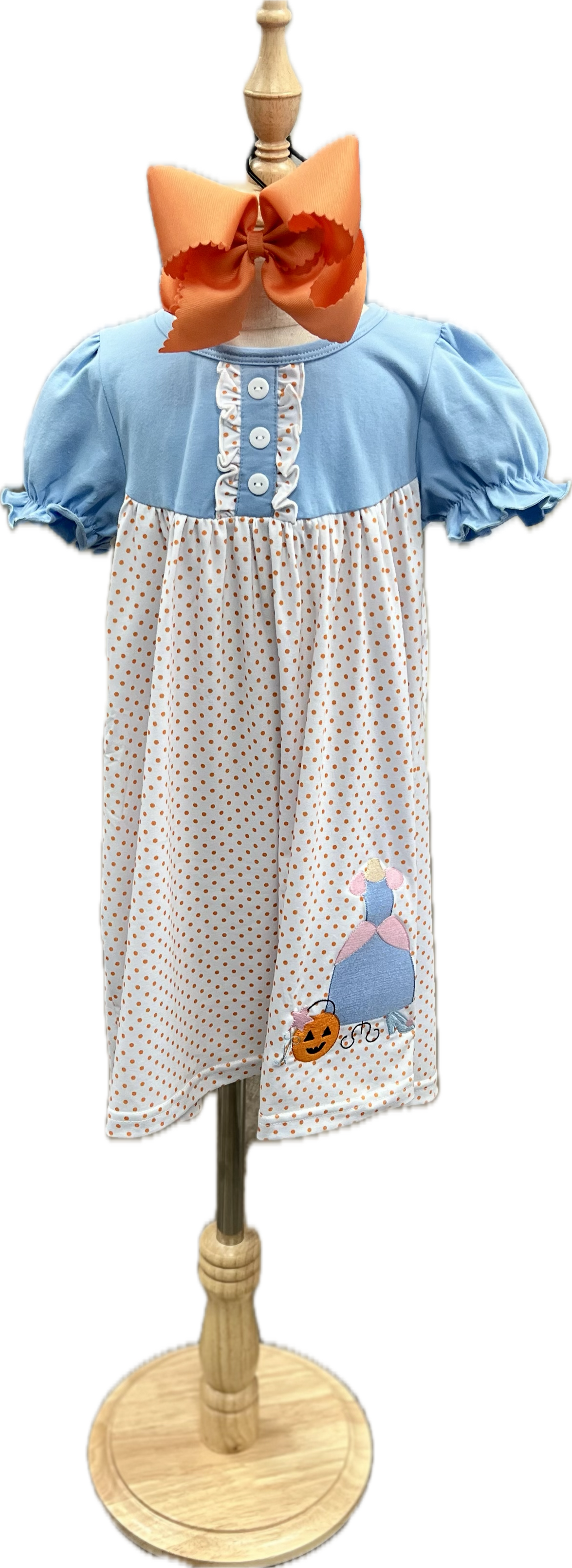 Children's dress with polka dot pattern and embroidered design on a mannequin.