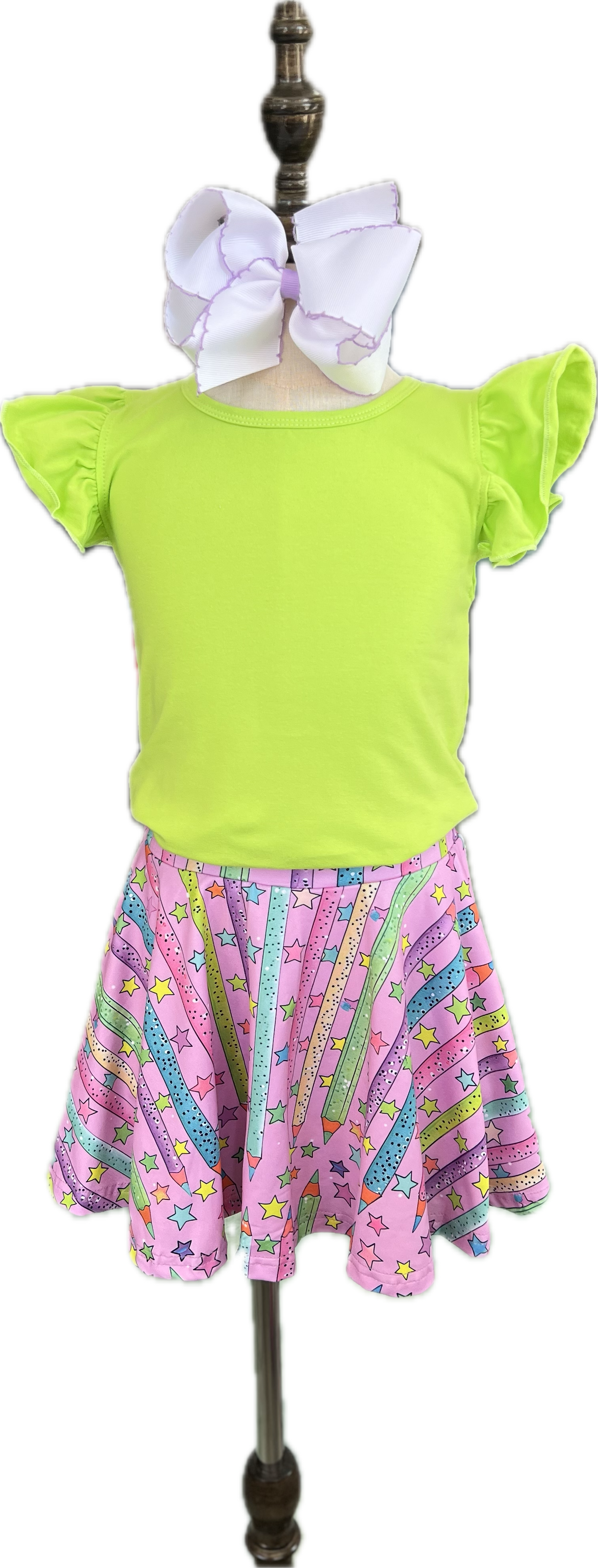 Green top and pink skirt with star pattern on a mannequin against a white background