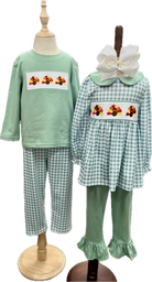 Children's green outfit with checkered pants and embroidered designs on a mannequin.