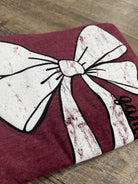 Maroon and white decorative bow on a wooden floor