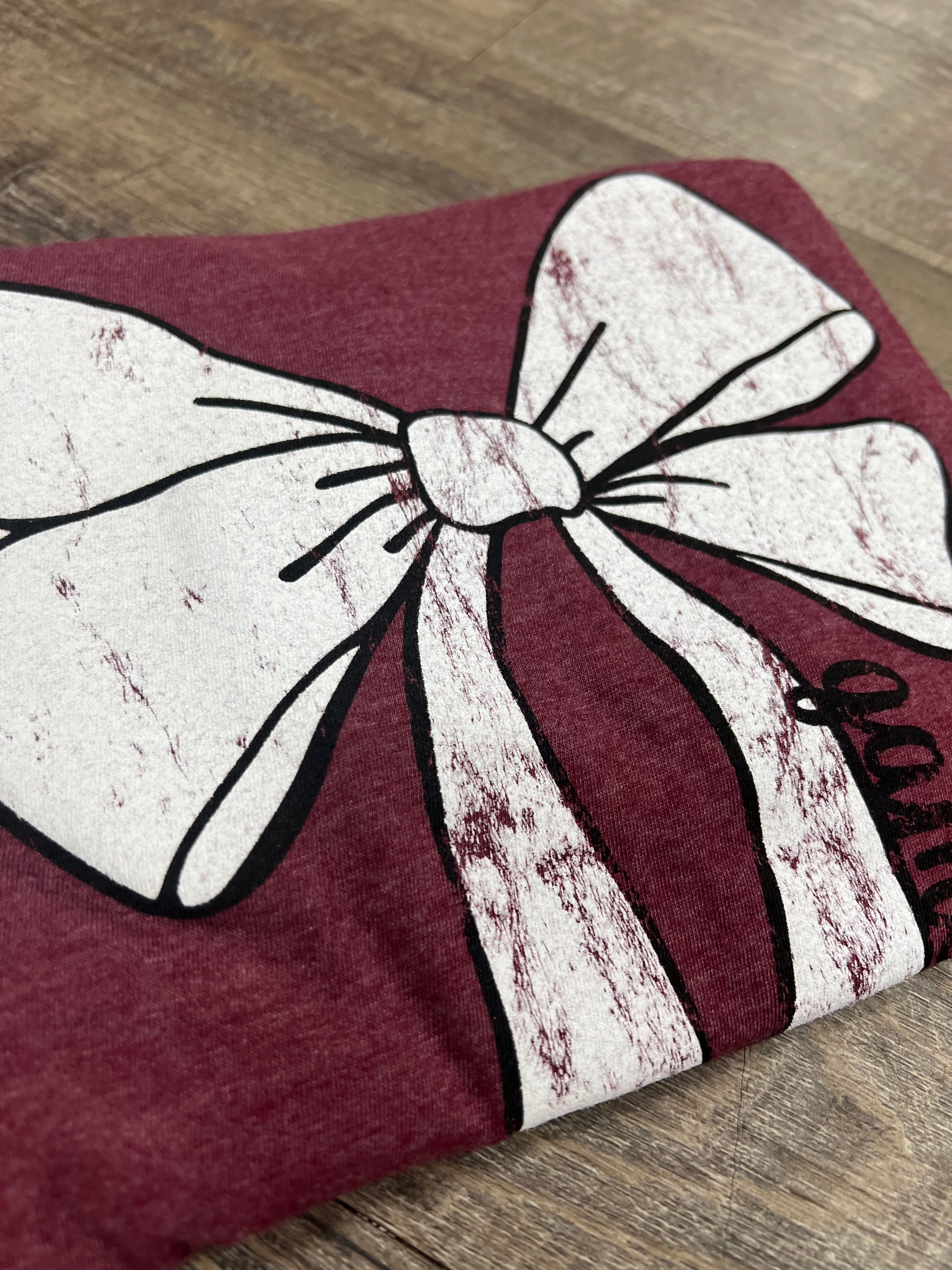 Maroon and white decorative bow on a wooden floor