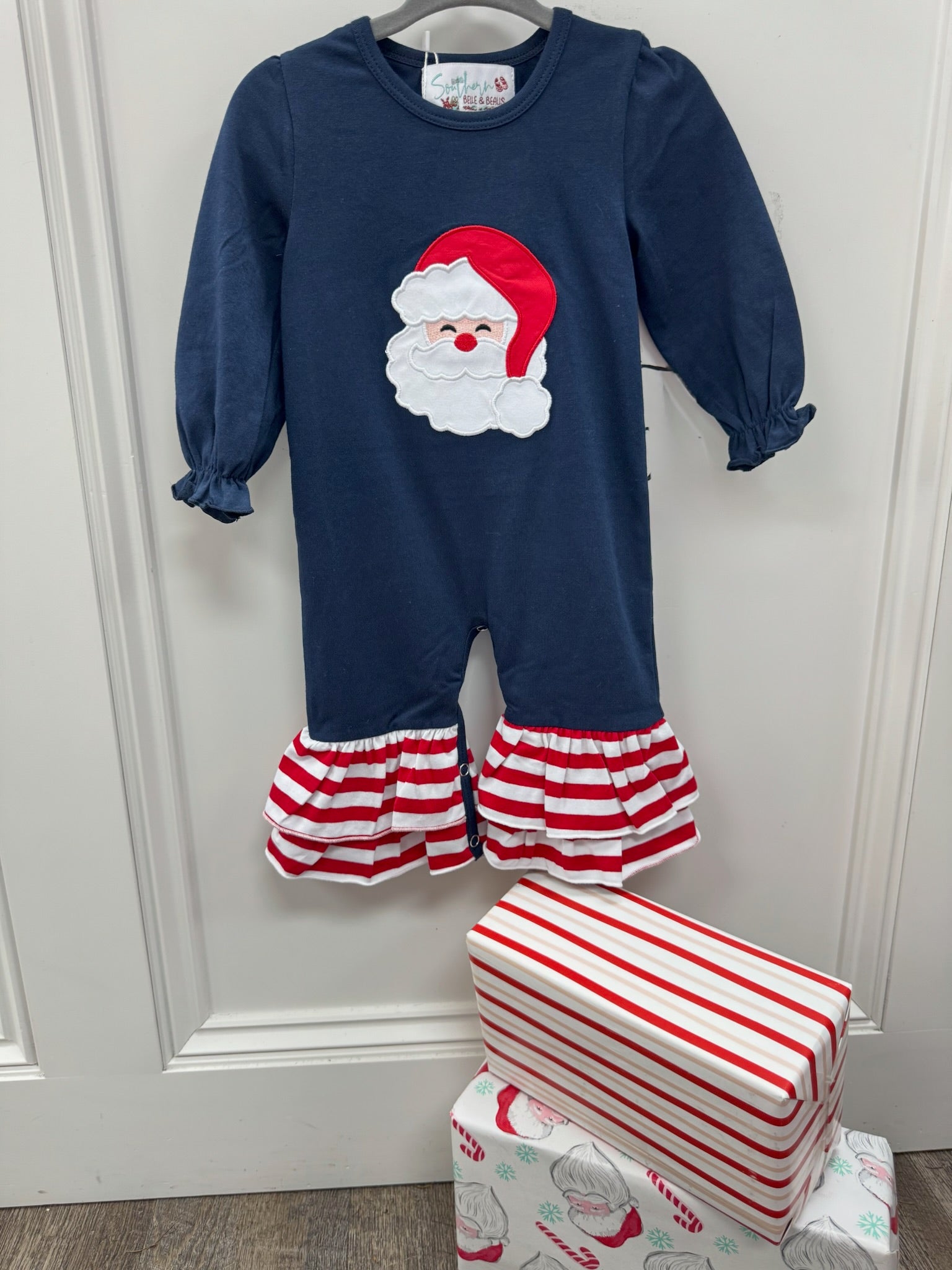 Long sleeve navy romper with Santa applique' and red & white ruffles on the pants. 