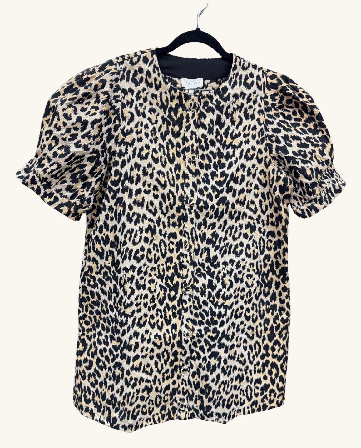 Leopard print button-front blouse with short puff sleeves and a round neckline, featuring a bold tan, black, and cream animal print pattern.