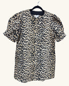 Leopard print button-front blouse with short puff sleeves and a round neckline, featuring a bold tan, black, and cream animal print pattern.