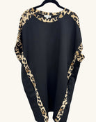 Black shift dress with leopard print trim along the neckline, sleeves, and side panels, featuring a relaxed batwing silhouette.