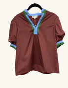 Rust-colored short-sleeve blouse with a split neckline, trimmed in contrasting blue and green accents, featuring a relaxed fit and gathered sleeve hems.