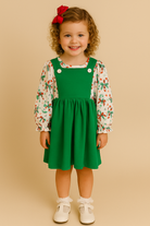 Little girl in green Christmas pinafore dress and candy cane bow print top, toddler holiday outfit, Southern Belle & Beaus boutique clothing.