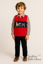 a red knit sweater vest detailed with a vintage train design, a red and navy gingham button-down shirt, and soft navy corduroy pants.