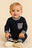 Baby wearing a navy blue outfit with white stripes on a beige background