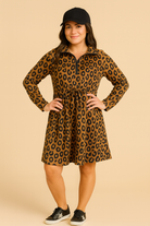 Woman wearing a leopard print dress and black cap on a beige background