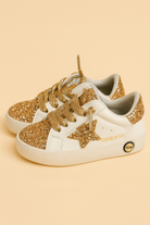 White sneakers with gold glittery details and a star design on a beige background