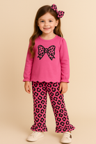 Young girl wearing a pink outfit with a large bow design on a beige background