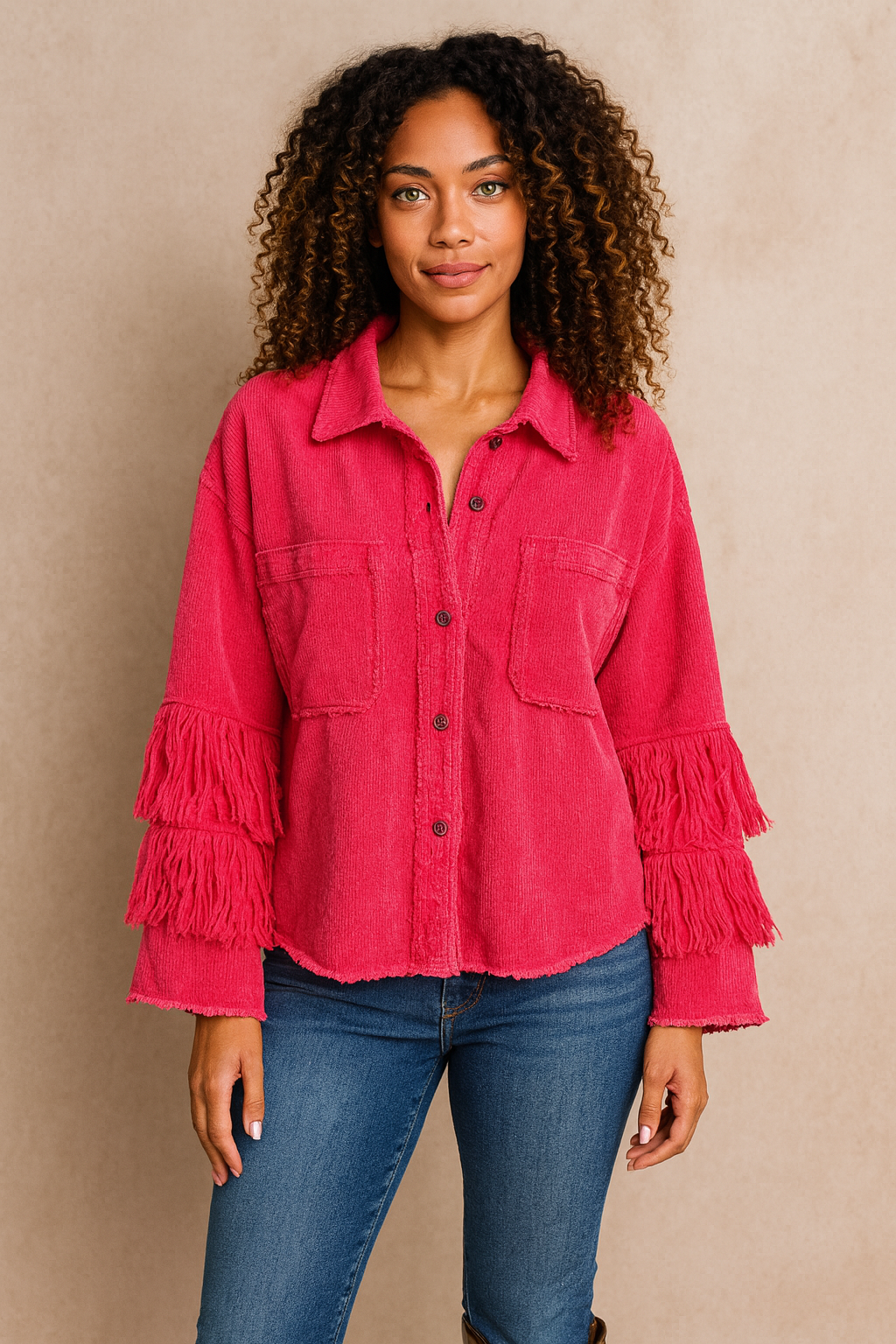 Woman wearing a pink fringed shirt and blue jeans against a beige background