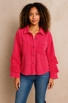 Woman wearing a pink fringed shirt and blue jeans against a beige background