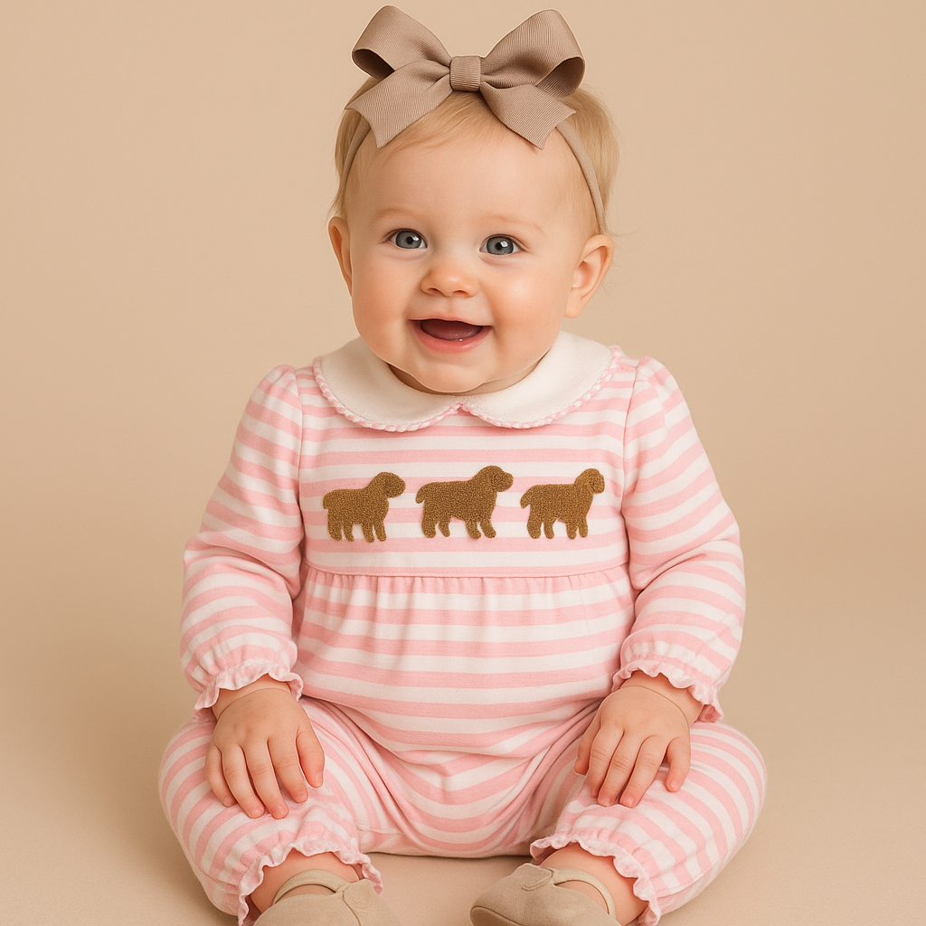 Baby wearing a pink and white striped outfit with gold sheep designs on a beige background