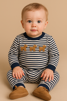 Baby wearing a striped outfit with lion designs on a beige background