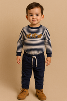Child wearing a striped shirt with reindeer design and navy pants on a beige background