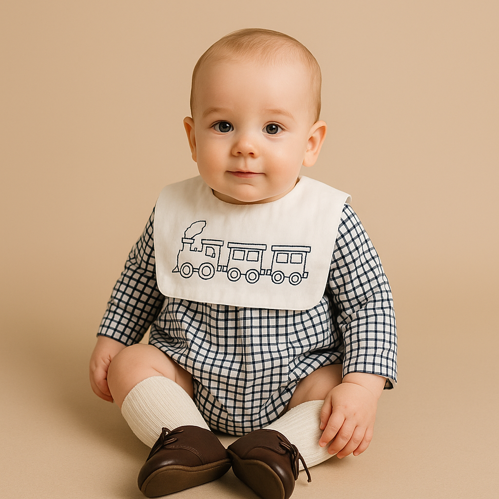 Baby wearing a checkered outfit with a train-themed bib on a beige background