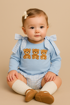 Baby wearing a blue outfit with teddy bear design on a beige background
