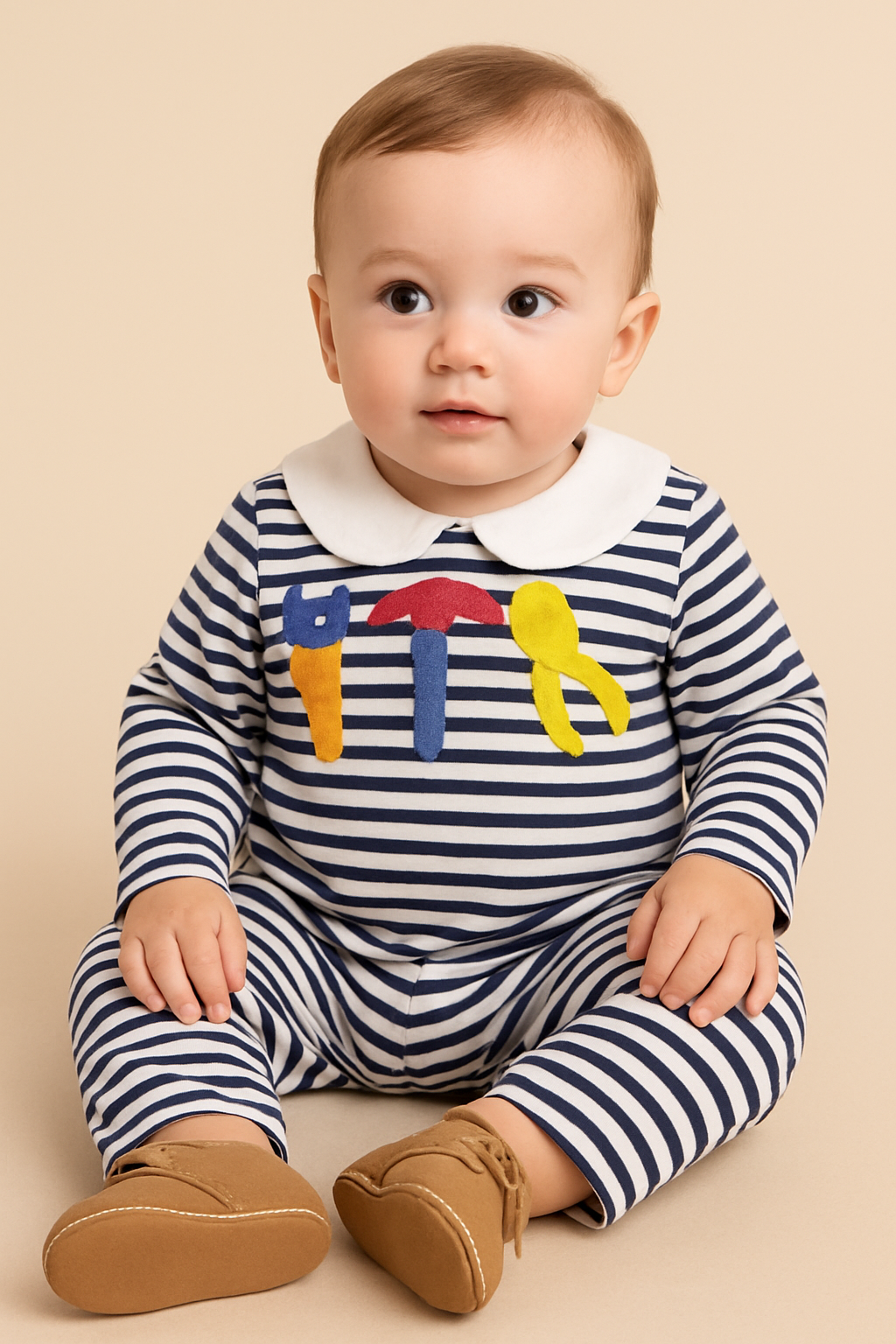 Baby wearing a striped outfit with colorful letters on a beige background
