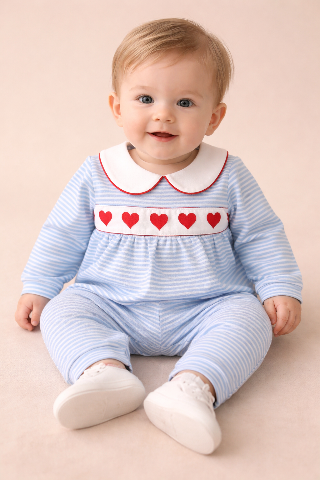 Baby boy wearing a blue and white striped romper with hearts across the chest. 
