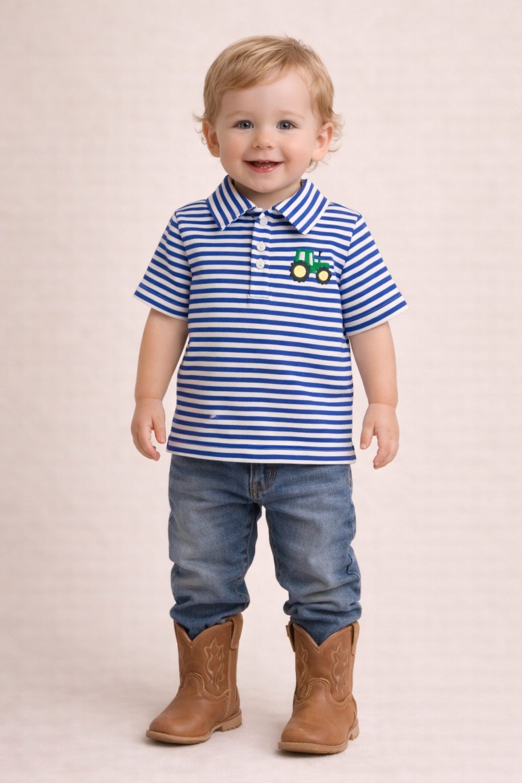 Child wearing a striped polo shirt with a tractor design, blue jeans, and brown boots on a beige background