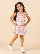 Young girl wearing a sleeveless top and skirt with American flag pattern on a beige background