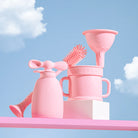 Set of pink baby utensils against a blue sky with clouds