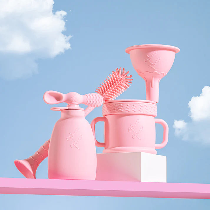 Set of pink baby utensils against a blue sky with clouds