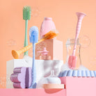 Collection of colorful baby bottle cleaning brushes and tools on a pink background
