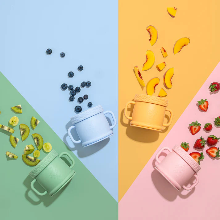 Colorful children's sippy cups with fruits on a multicolored background