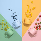 Colorful children's sippy cups with fruits on a multicolored background